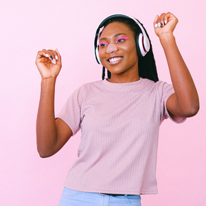 A girl wearing a pink shirt listening to headphones and dancing with Nöz sunscreen on her nose